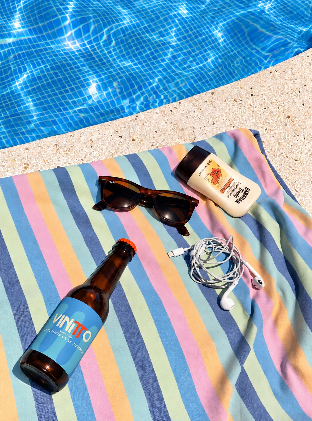 Botellín Vinitto junto a la piscina con toalla y accesorios de verano